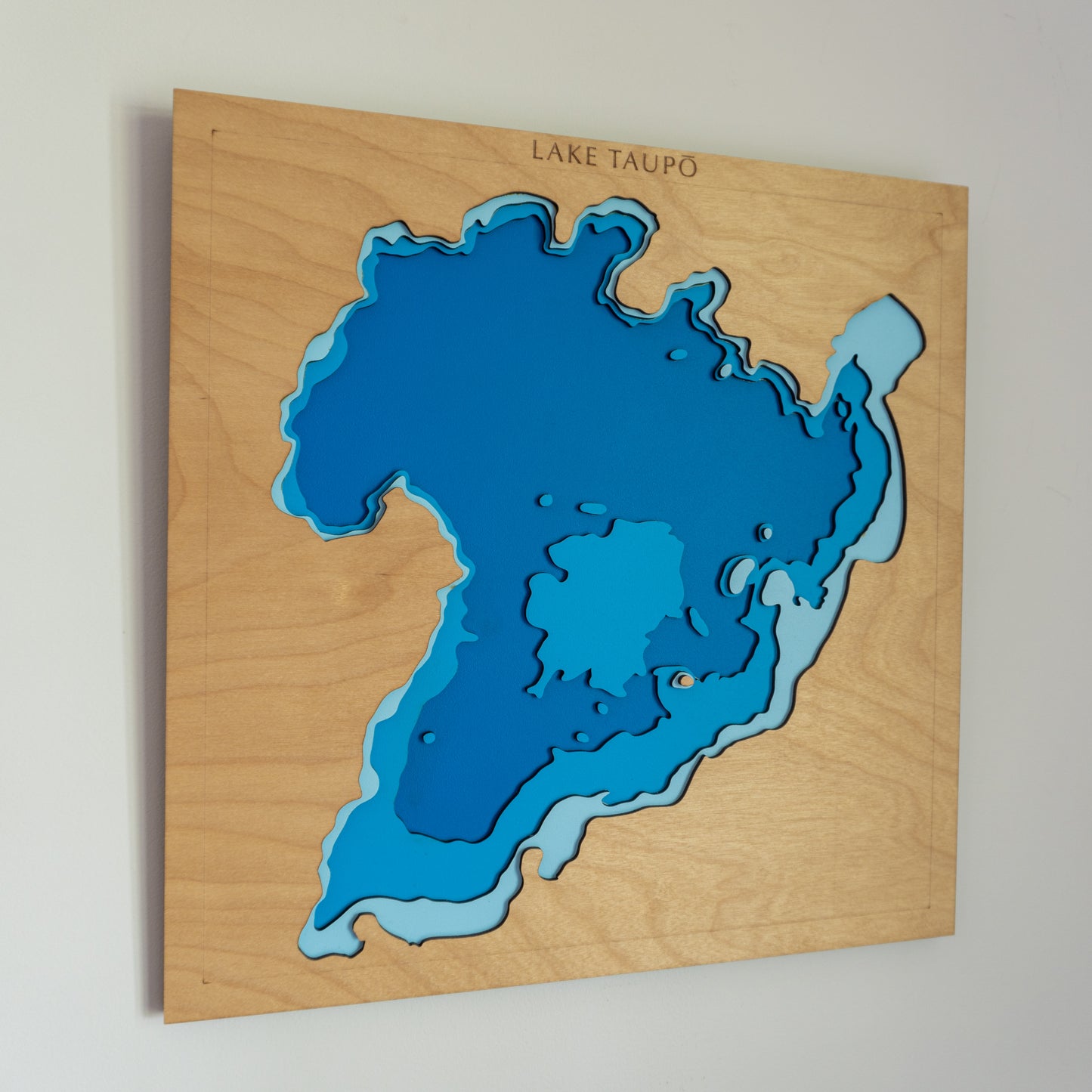 Close-up view of a custom small wooden depth map showing detailed laser-cut bathymetric layers and personalized coastal features.