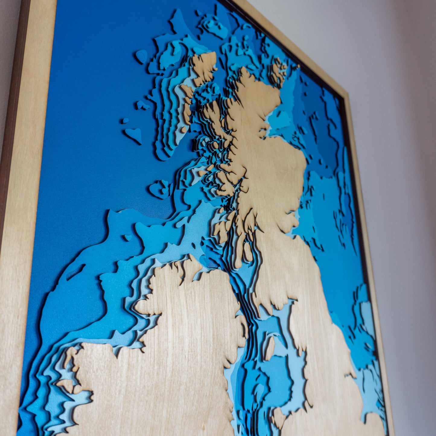Close-up view of the United Kingdom wooden map showing detailed laser-cut bathymetric layers and coastal features.