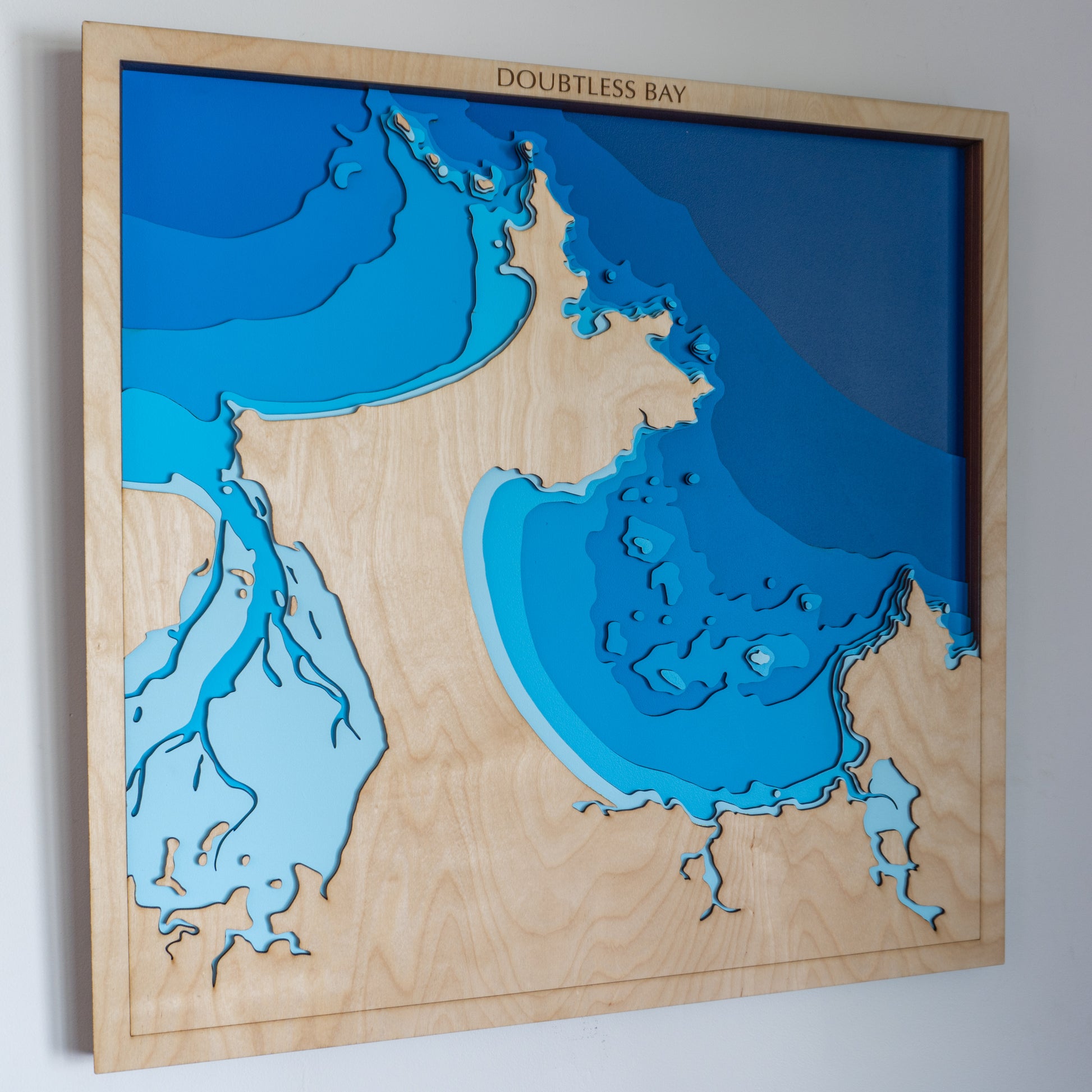 Handcrafted wooden depth map of Doubtless Bay, Northland, New Zealand, showcasing laser-cut layers depicting the bay's intricate coastline and bathymetric contours.