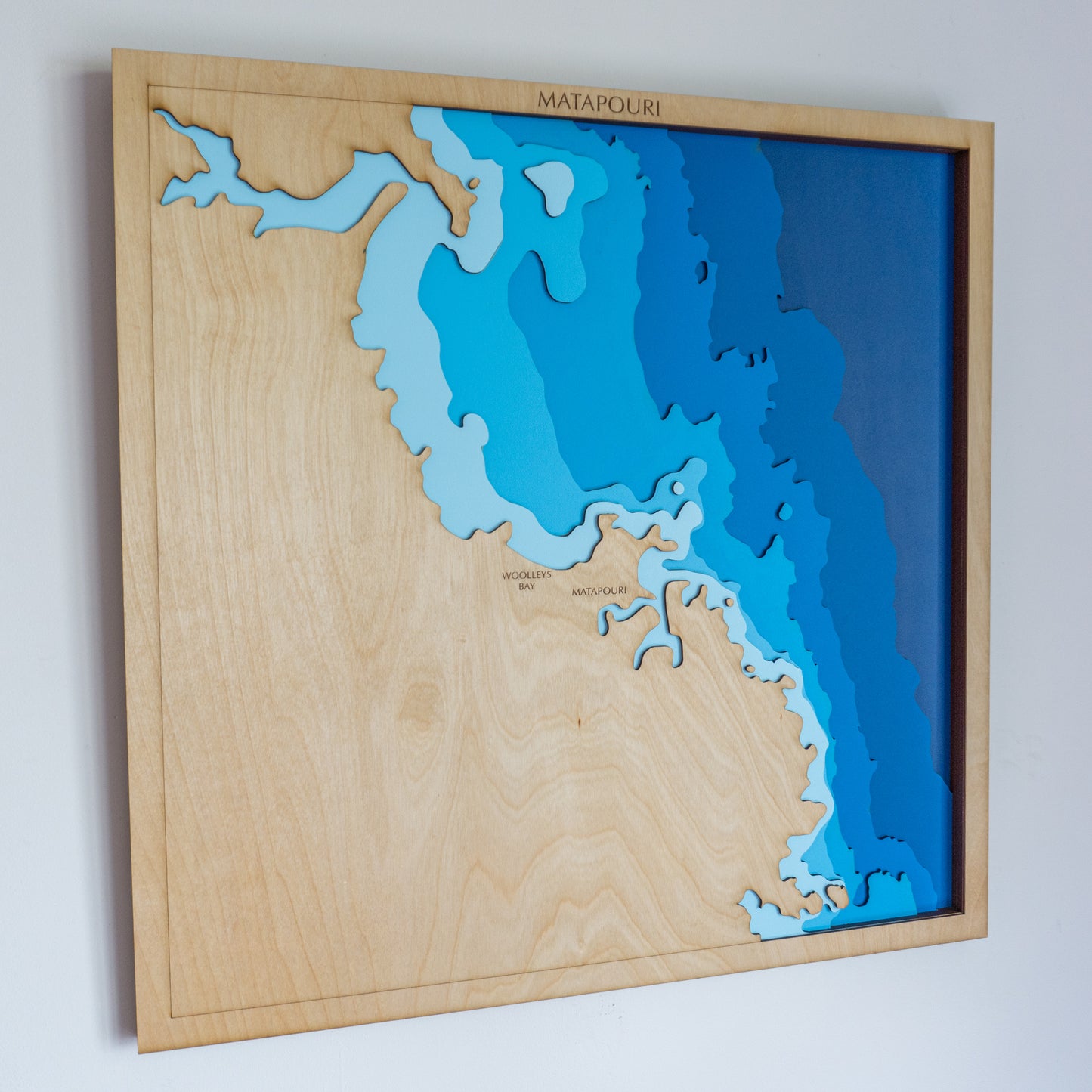 Handcrafted wooden depth map of Matapōuri and Whananaki coastline in Northland, New Zealand, featuring laser-cut birch layers depicting sea depths from sea level to -68 meters