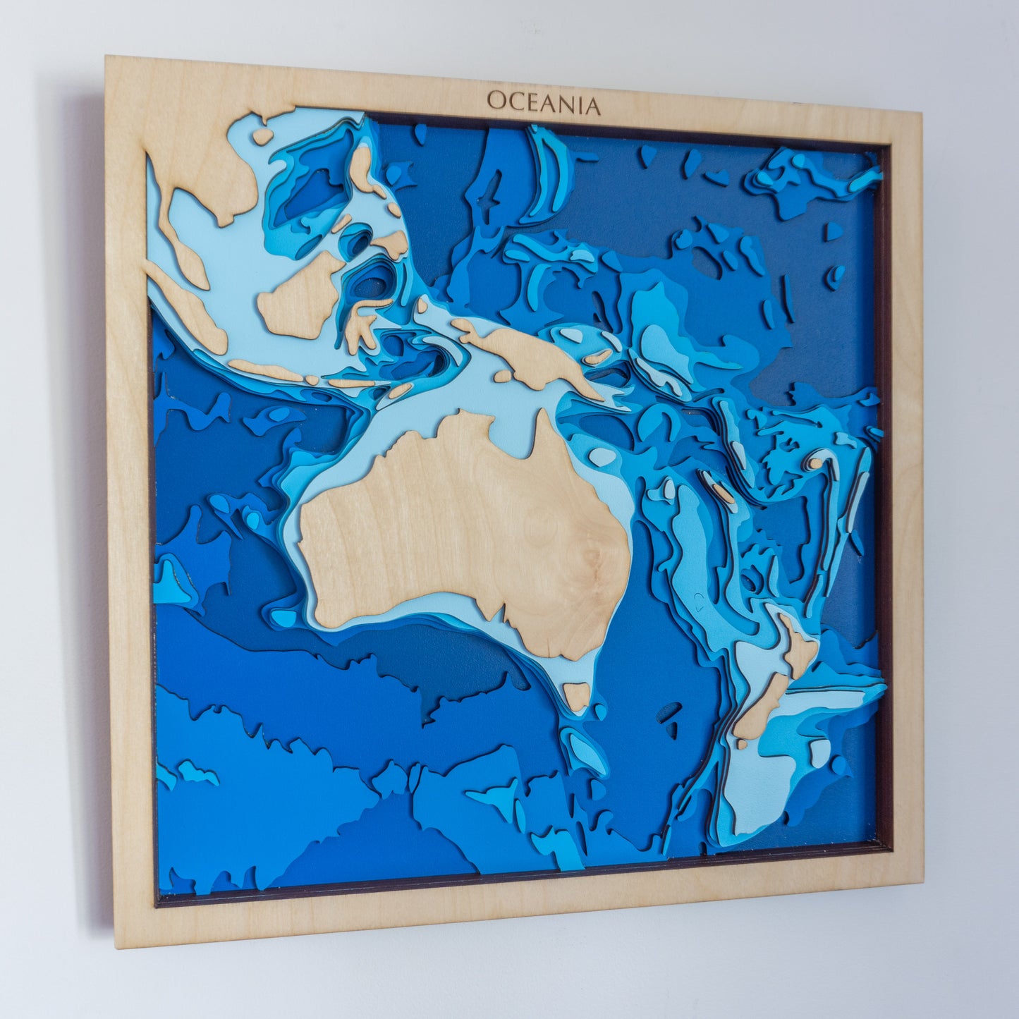Handcrafted wooden depth map of Oceania, showcasing laser-cut layers depicting Australia's landmass, New Zealand, and the Pacific islands, highlighting the region's diverse bathymetry.