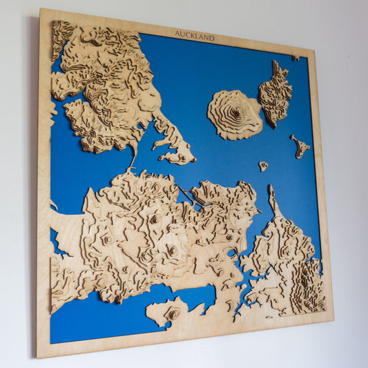 Handcrafted wooden topographic map of Auckland, New Zealand, featuring laser-cut European Birch layers illustrating elevations from sea level up to 200 meters, highlighting volcanic cones including Rangitoto Island