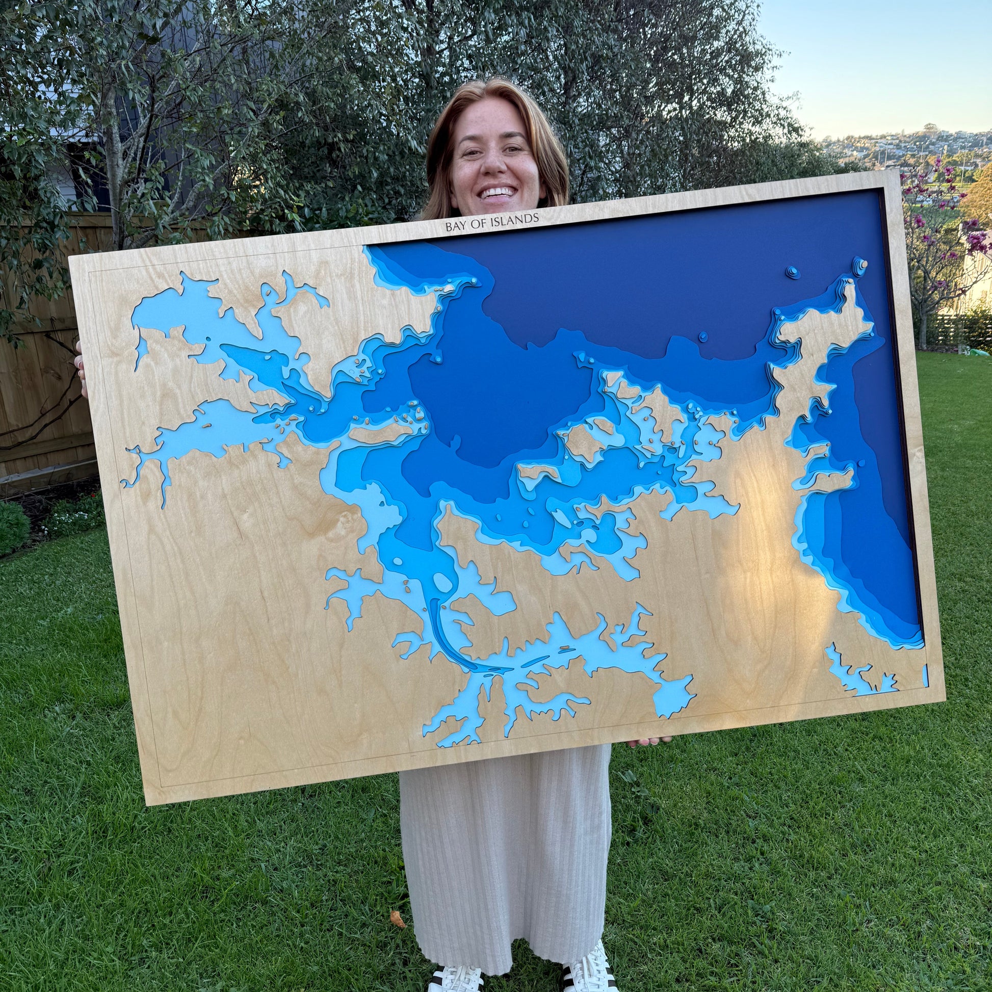 Person holding a large wooden topographic map outdoors