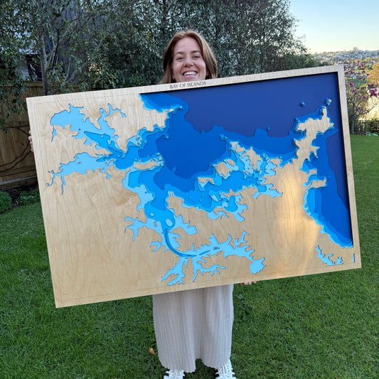 Person holding a large wooden topographic map outdoors