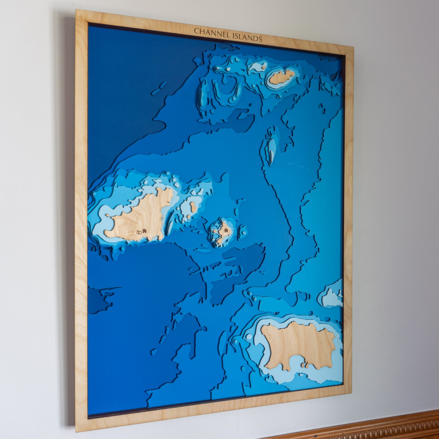 Handcrafted wooden depth map of the Channel Islands, featuring laser-cut layers depicting the archipelago's rugged coastlines, sandy beaches, and surrounding bathymetric contours.