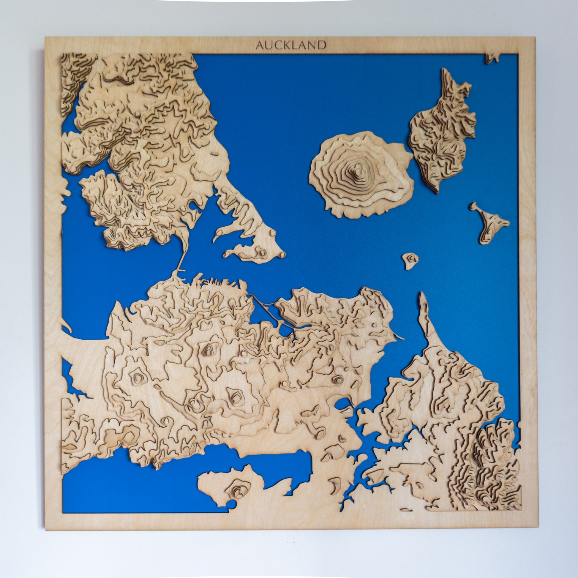 Close-up view of the Auckland topographic wooden map showing detailed laser-cut elevation layers and volcanic landforms.