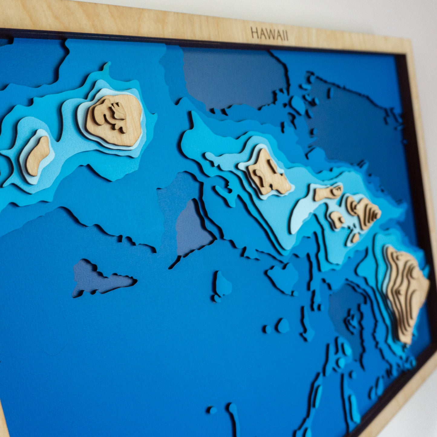Close-up view of the Hawai‘i XL wooden map showing detailed laser-cut bathymetric layers and coastal features.