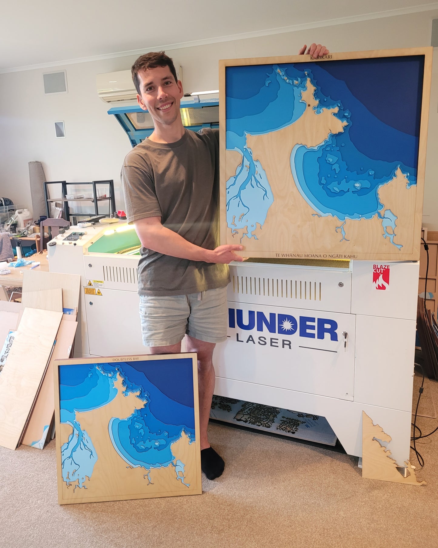 Side-by-side comparison of Medium and XL handcrafted wooden depth maps of Doubtless Bay, New Zealand, showing size difference, detail clarity, and visual impact.