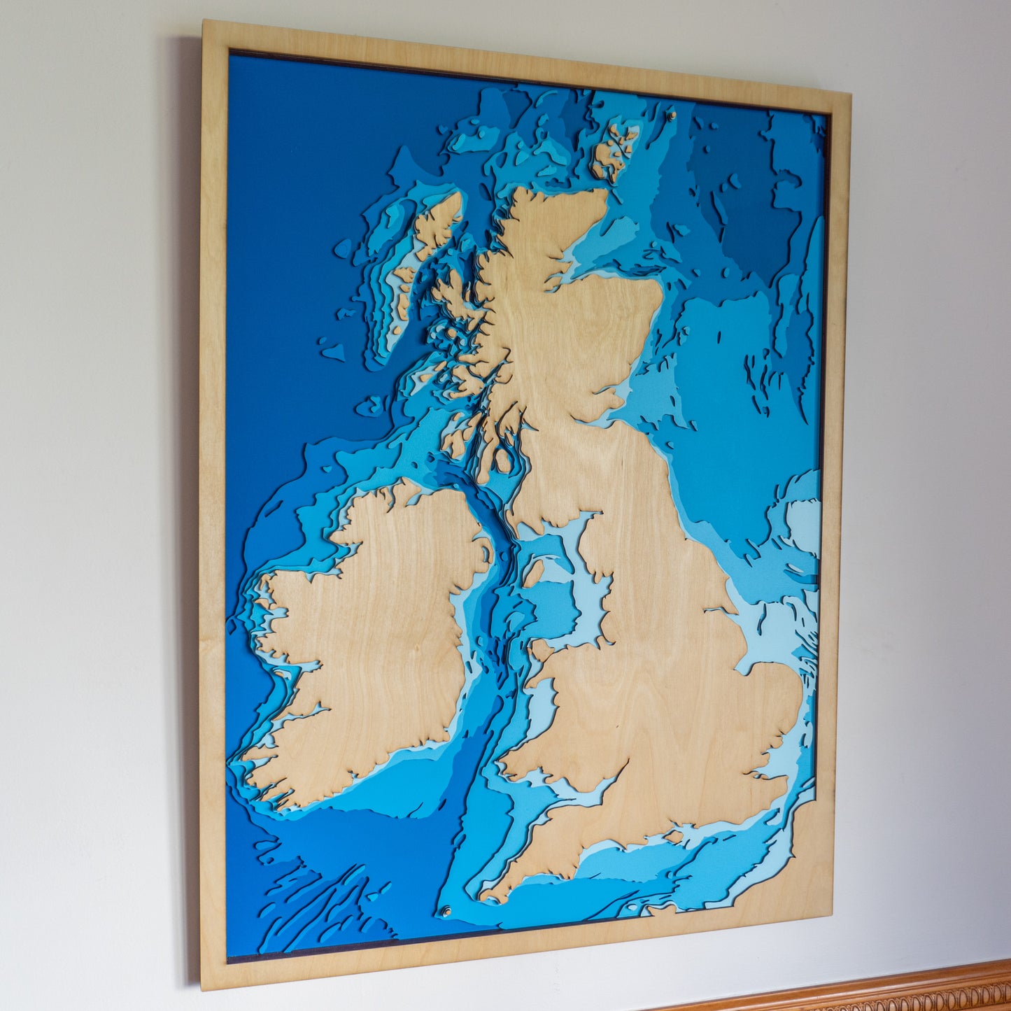 Handcrafted wooden depth map of the United Kingdom, featuring laser-cut European Birch layers illustrating sea depths from sea level to -500 meters, highlighting the UK's intricate coastlines and surrounding bathymetric contours.