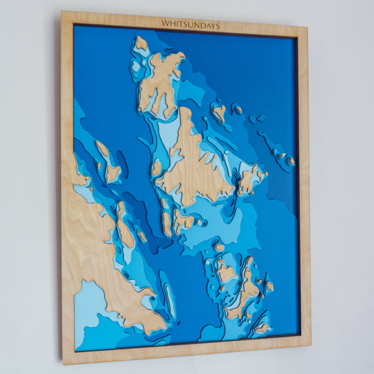 Handcrafted wooden depth map of the Whitsunday Islands, showcasing laser-cut layers depicting the region's crystal-clear waters, vibrant coral reefs, and pristine beaches.